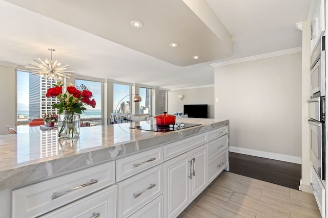 kitchen featuring baseboards, ornamental molding, black electric cooktop, and white cabinets