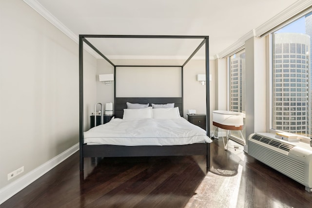 bedroom featuring a wall unit AC, baseboards, crown molding, and wood finished floors