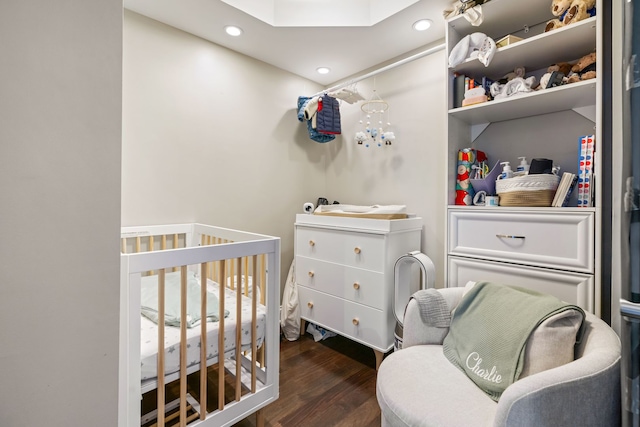 bedroom featuring a nursery area, a skylight, recessed lighting, and wood finished floors