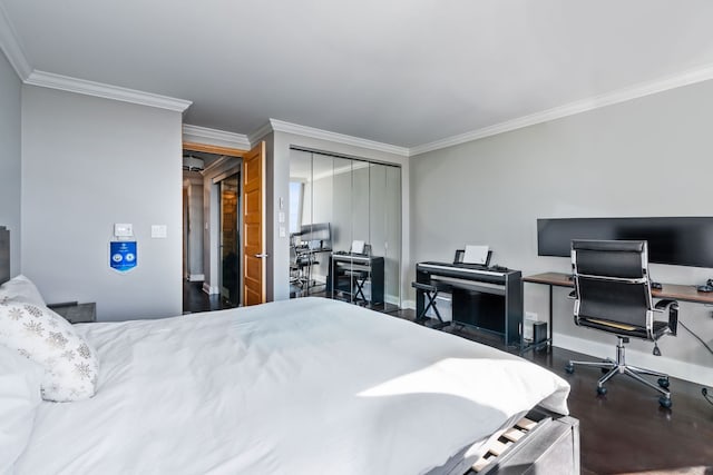 bedroom featuring a closet, crown molding, baseboards, and wood finished floors