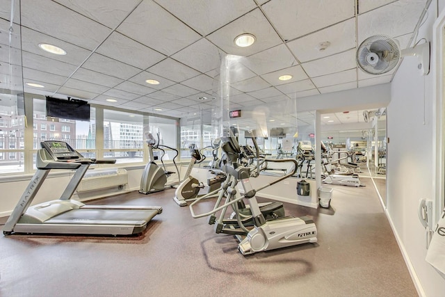 workout area featuring a paneled ceiling and baseboards