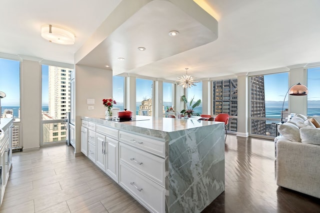 kitchen featuring light wood finished floors, white cabinets, open floor plan, expansive windows, and black electric stovetop