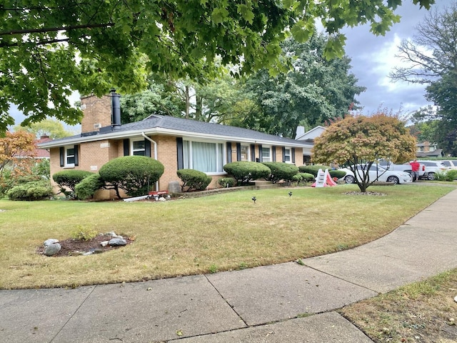 ranch-style home featuring a chimney, a front lawn, and brick siding