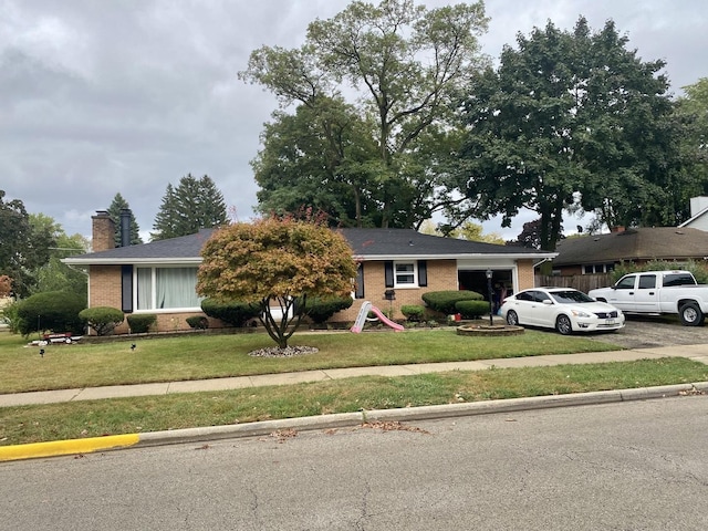 ranch-style home with aphalt driveway, an attached garage, brick siding, a chimney, and a front yard