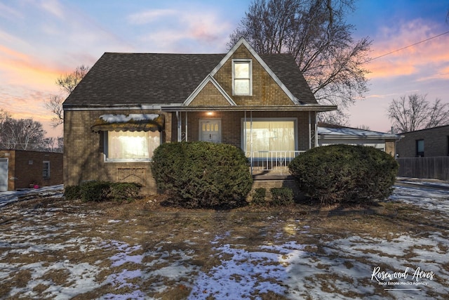 view of front of house featuring brick siding and roof with shingles