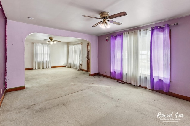 spare room with baseboards, visible vents, arched walkways, and a ceiling fan