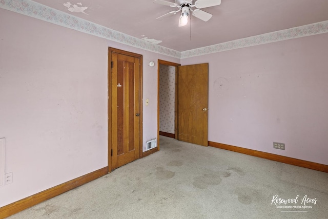 spare room featuring light carpet, visible vents, baseboards, and ceiling fan