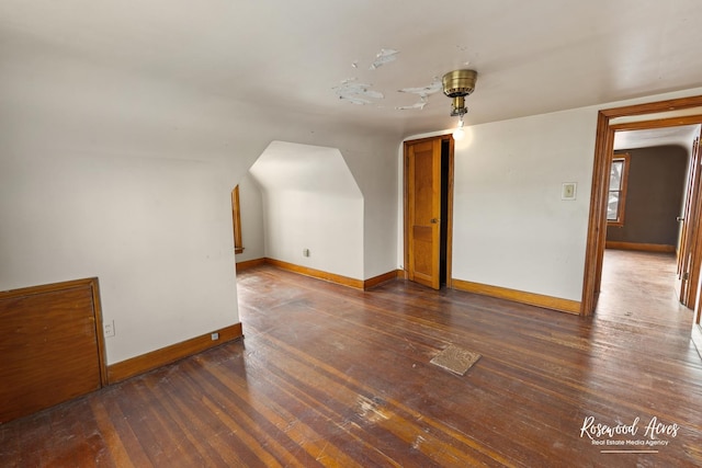 additional living space featuring baseboards and dark wood-type flooring