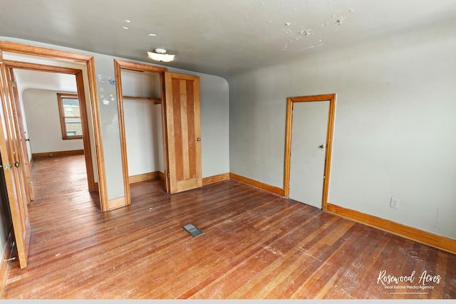 unfurnished bedroom featuring a closet, wood finished floors, visible vents, and baseboards