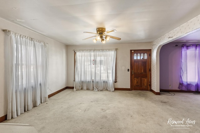 entrance foyer with arched walkways, light carpet, and baseboards