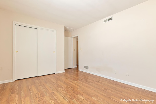 unfurnished bedroom featuring baseboards, a closet, visible vents, and light wood-style floors