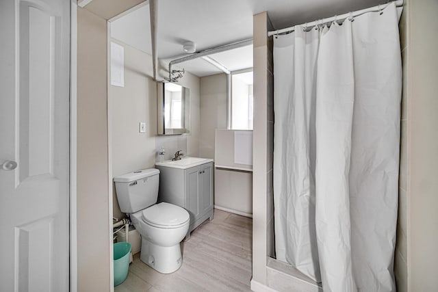 bathroom with curtained shower, vanity, toilet, and wood finished floors