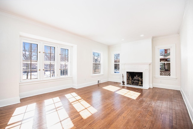 unfurnished living room featuring a fireplace with flush hearth, ornamental molding, baseboards, and wood finished floors