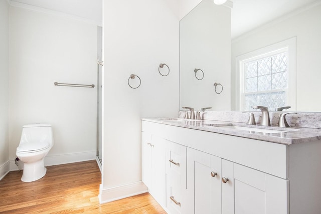 bathroom featuring crown molding, toilet, vanity, wood finished floors, and baseboards