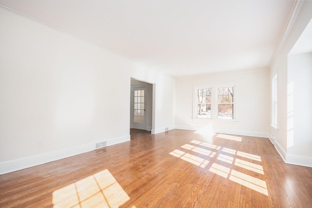 unfurnished room with visible vents, wood finished floors, and ornamental molding