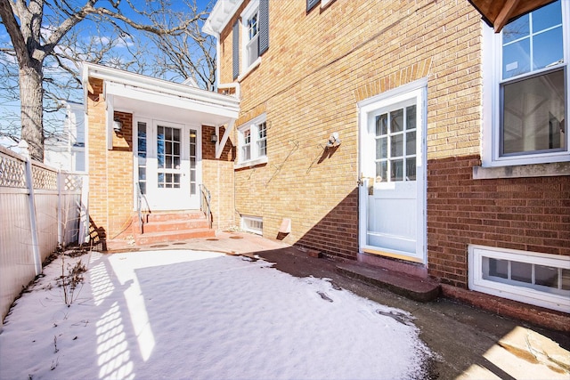 doorway to property with a patio area, fence, and brick siding