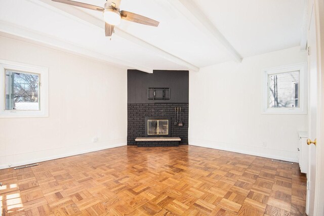 unfurnished living room with beam ceiling, visible vents, a brick fireplace, ceiling fan, and baseboards