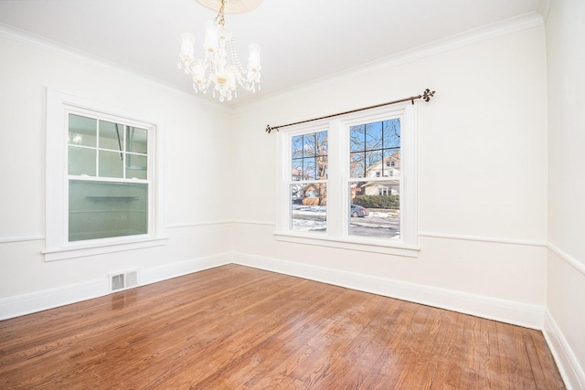 spare room featuring baseboards, visible vents, wood finished floors, crown molding, and a notable chandelier