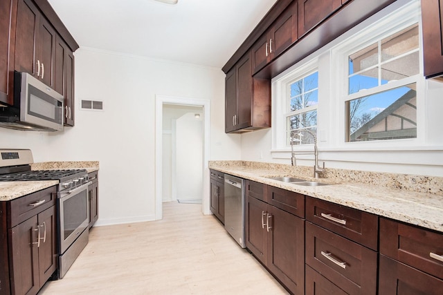 kitchen with visible vents, appliances with stainless steel finishes, light wood-style floors, a sink, and light stone countertops