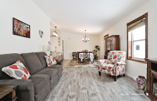 living area with baseboards, light wood-type flooring, and a notable chandelier