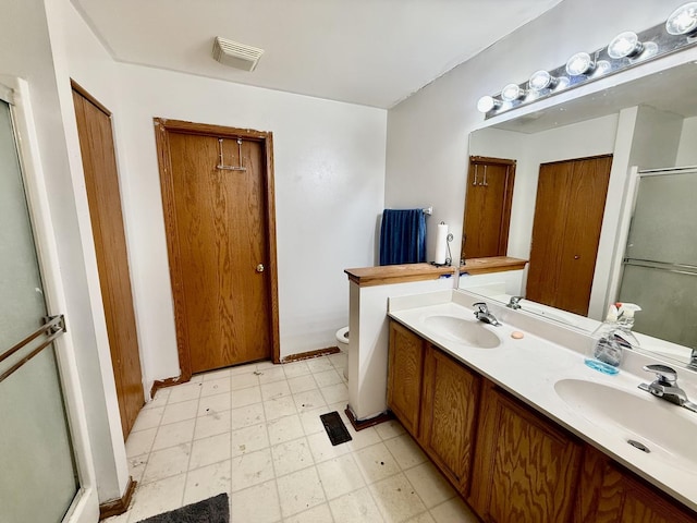 full bath with a shower with shower door, a sink, toilet, and tile patterned floors