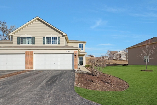 traditional-style home featuring an attached garage, aphalt driveway, a front lawn, and brick siding