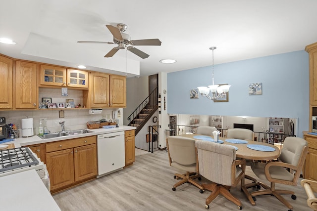 kitchen featuring white appliances, glass insert cabinets, light countertops, pendant lighting, and a sink