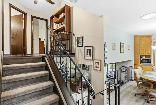 staircase with a ceiling fan and wood finished floors