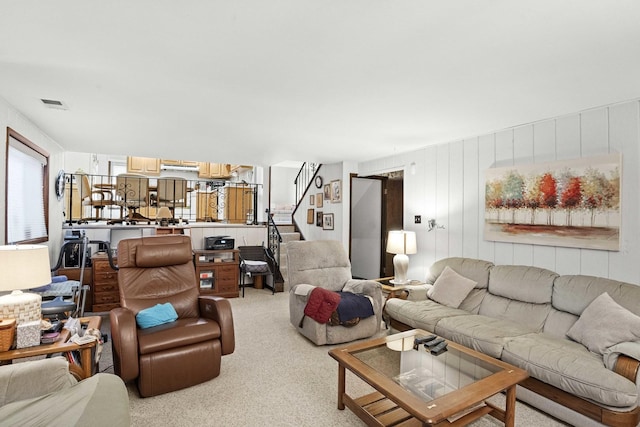 living area with light carpet, visible vents, and stairway