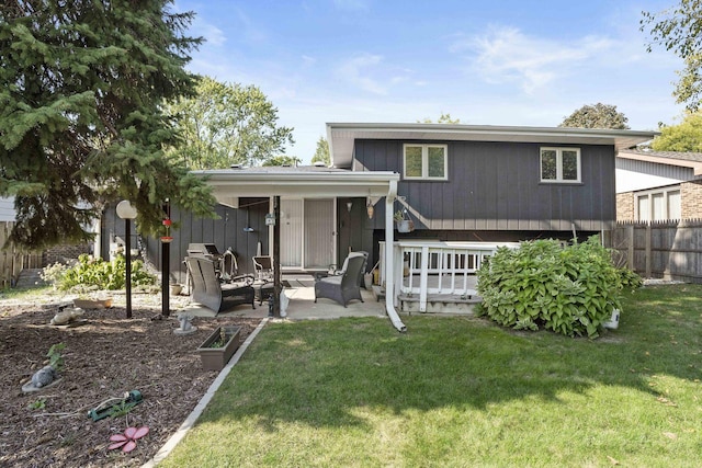 rear view of property featuring a lawn, a patio area, and fence