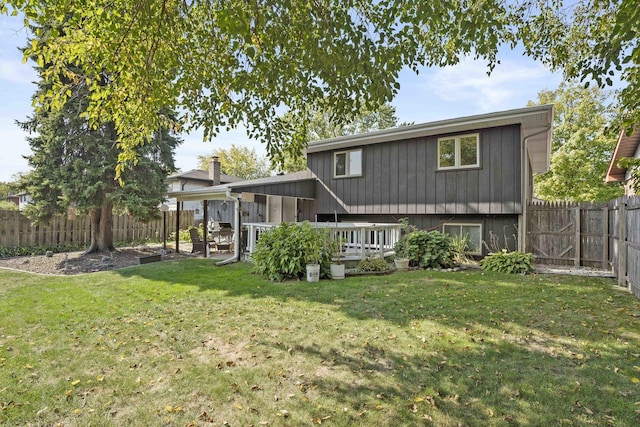 rear view of house featuring a fenced backyard, a yard, and a deck