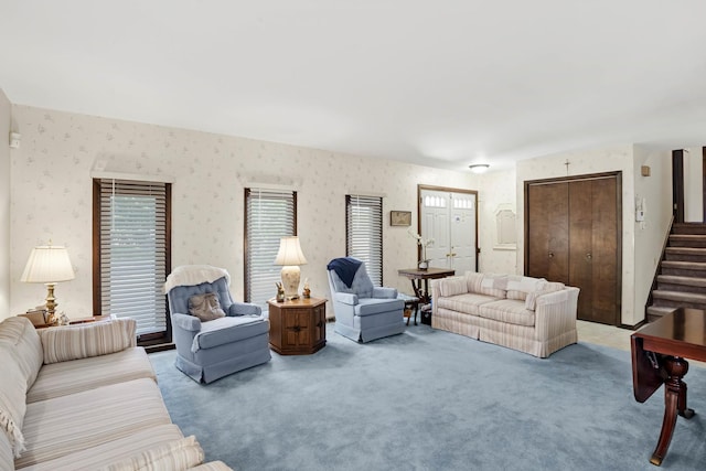 living area with light carpet, wallpapered walls, and stairs