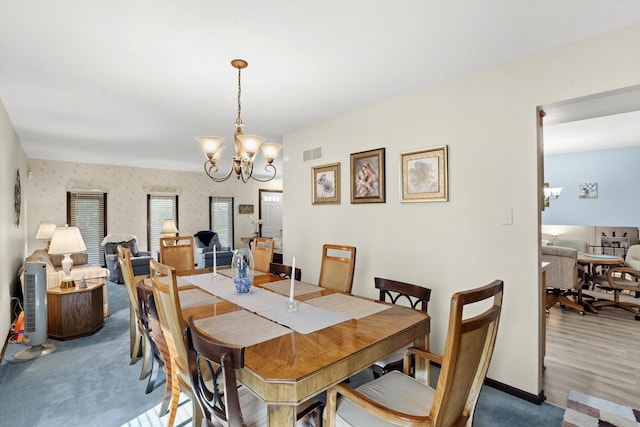 dining room featuring a chandelier, visible vents, baseboards, and wallpapered walls