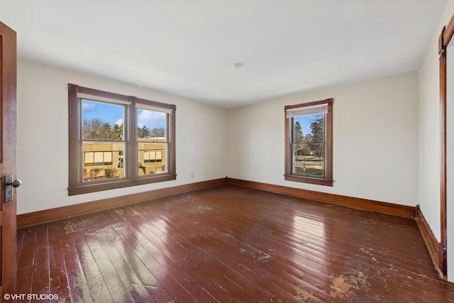 empty room with dark wood-style flooring, a healthy amount of sunlight, and baseboards