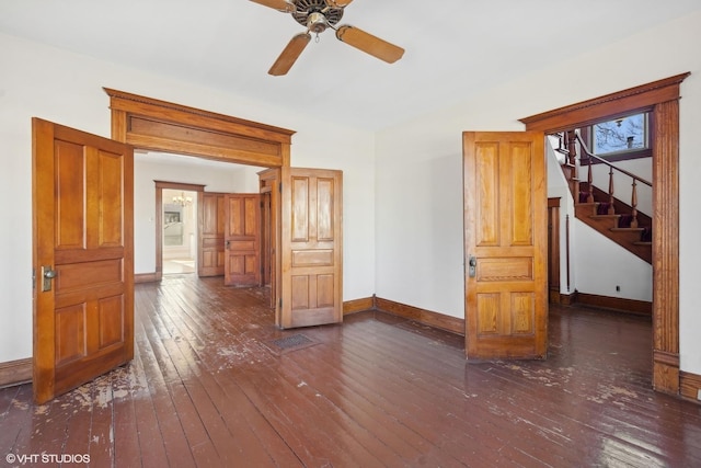 empty room featuring a ceiling fan, dark wood-style flooring, stairway, and baseboards