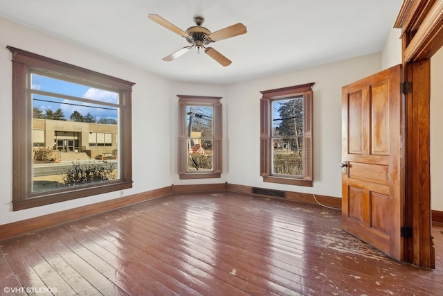 spare room featuring dark wood-style floors, ceiling fan, and baseboards