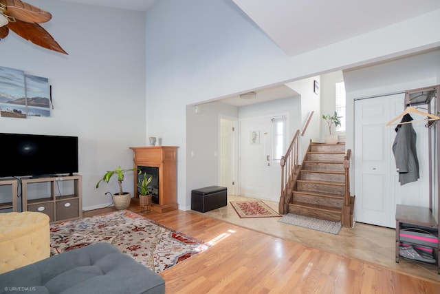 living area with a high ceiling, stairway, a fireplace, and light wood-style floors