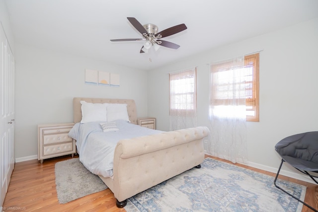 bedroom with light wood-style floors, ceiling fan, and baseboards