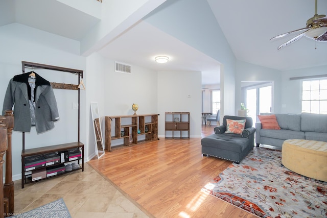 living area with visible vents, vaulted ceiling, ceiling fan, light wood-type flooring, and baseboards