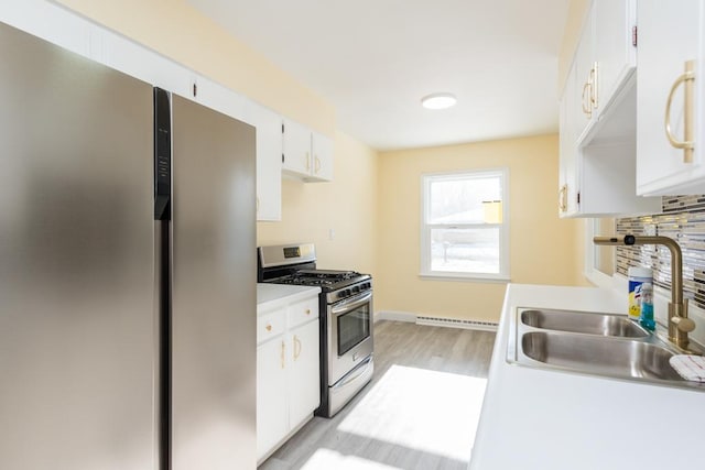 kitchen featuring stainless steel appliances, light countertops, decorative backsplash, white cabinets, and a sink