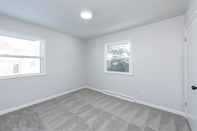 carpeted spare room with a baseboard heating unit and baseboards