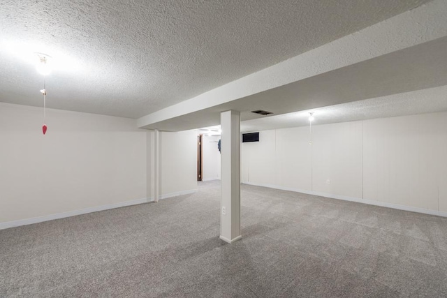 finished basement with visible vents, a textured ceiling, and carpet flooring