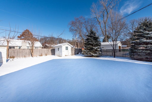 yard layered in snow featuring an outdoor structure, fence, and a shed