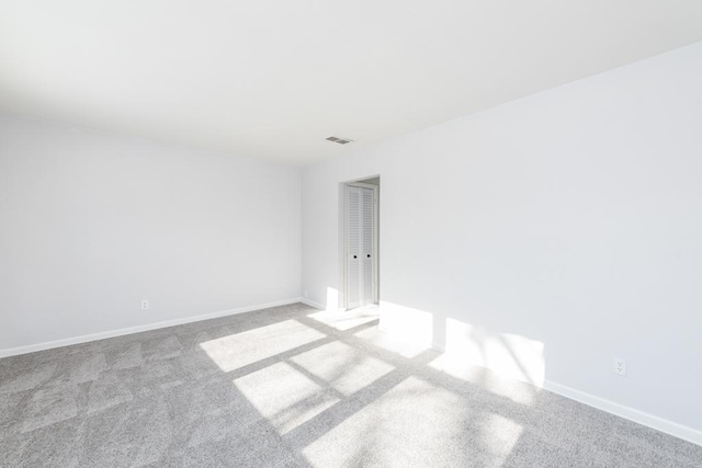 unfurnished room featuring light colored carpet, visible vents, and baseboards