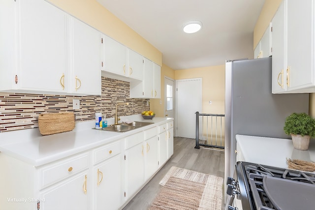 kitchen with white cabinetry, light countertops, a sink, and gas stove