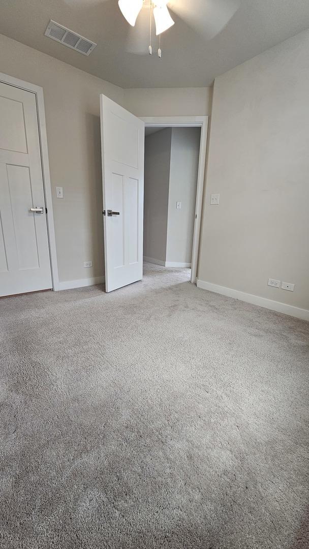 unfurnished room with baseboards, ceiling fan, light colored carpet, and visible vents