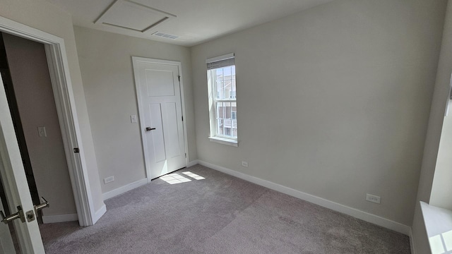 unfurnished bedroom featuring carpet floors, attic access, baseboards, and visible vents