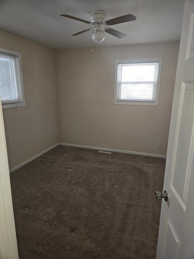 carpeted spare room featuring visible vents, a ceiling fan, and baseboards