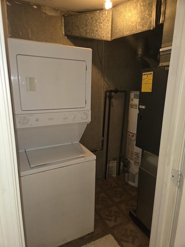 washroom with gas water heater, stacked washing maching and dryer, and laundry area