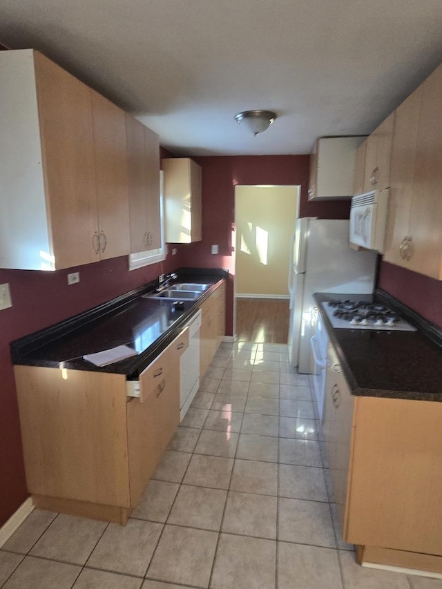 kitchen featuring white appliances, dark countertops, a sink, and light tile patterned flooring